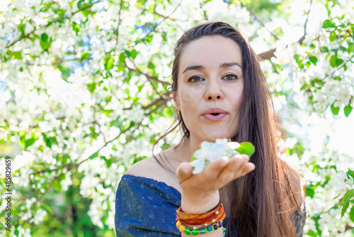 Happy brunette woman in blooming garden holding flowers