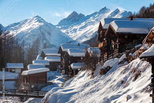 Village avec ses traditionnels chalets de bois au pied des montagnes du Valais, Suisse photo