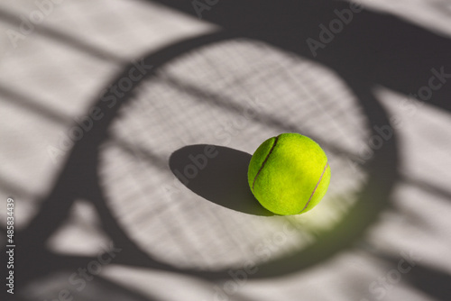 Tennis ball and its shadow on an isolated white background. Tennis ball has tennis racket and net shadow on it.