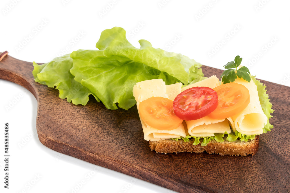 On a wooden kitchen board a sandwich with bread, lettuce, cheese, tomato slices. For a light breakfast. 