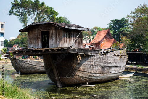 Broken ruins wood chinese sailing ship or damage wooden antique junk boat china style in pond of garden park for thai people travel visit in Wat Samphran temple at Sam Phran in Nakhon Pathom, Thailand
