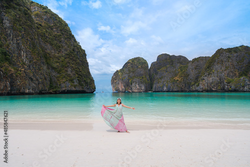 happy Asian woman tourist relax fun with a beautiful landscape view of Maya bay beach at Phi Phi Leh islands famous place in Krabi  Thailand. white sand and clear turquoise sea with cliffs in ocean.  