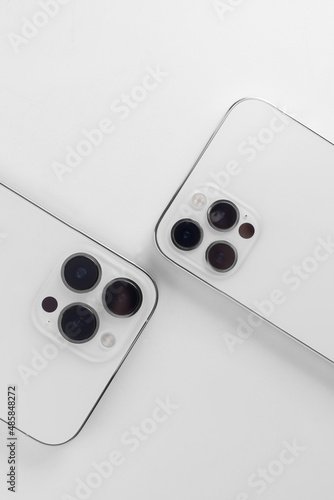  white smartphones on a white background lie with the cameras up. Iphone 12 pro, iphone 13 pro max