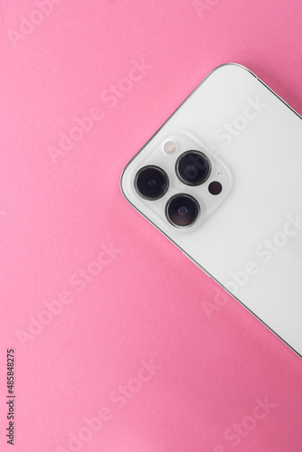 white phone with three cameras on a pink background. Iphone 13 pro max