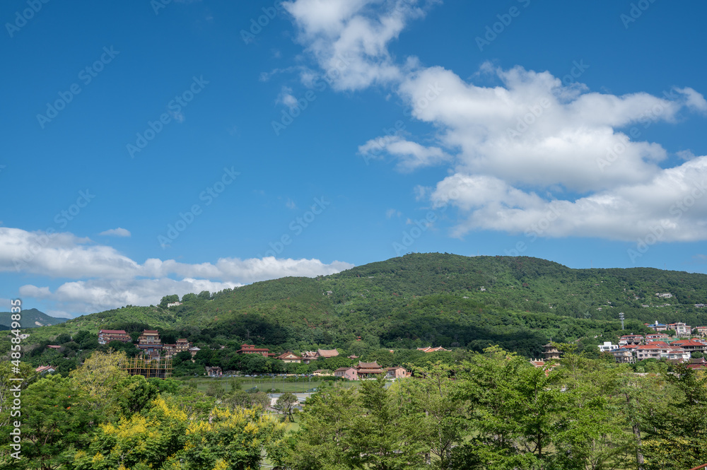 Under the blue sky and white clouds, the village is on the mountain