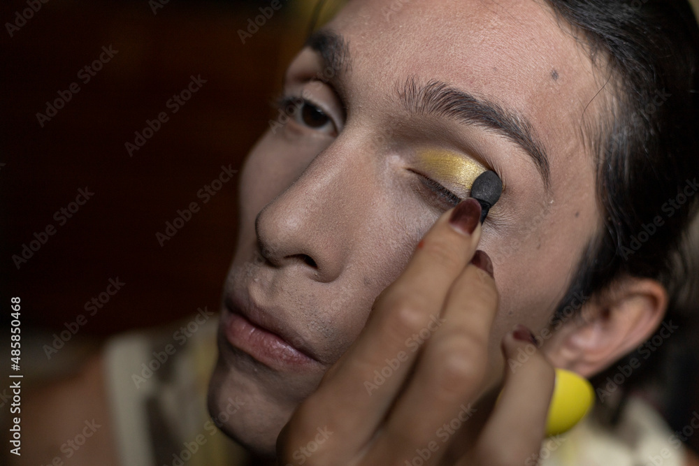 A transgender young man (22) is in his room putting on makeup. Concept of transgender