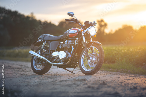 Fototapeta Naklejka Na Ścianę i Meble -  Caffeeracer Motorrad auf Feldweg im Sonnenuntergang
