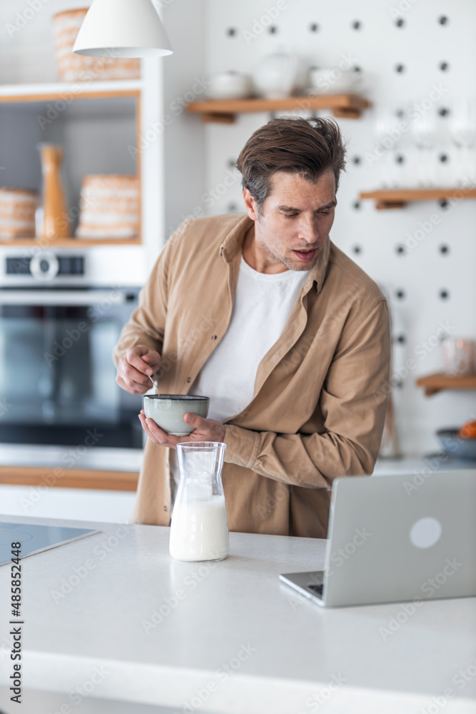 Middle-aged man multitasking he works while making a oatmeal for breakfast. Middle-aged man multitasking he works while making a oatmeal for breakfast.