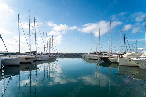Marina with boats reflected on the sea and blu sky with white clouds © Andrea Tosi