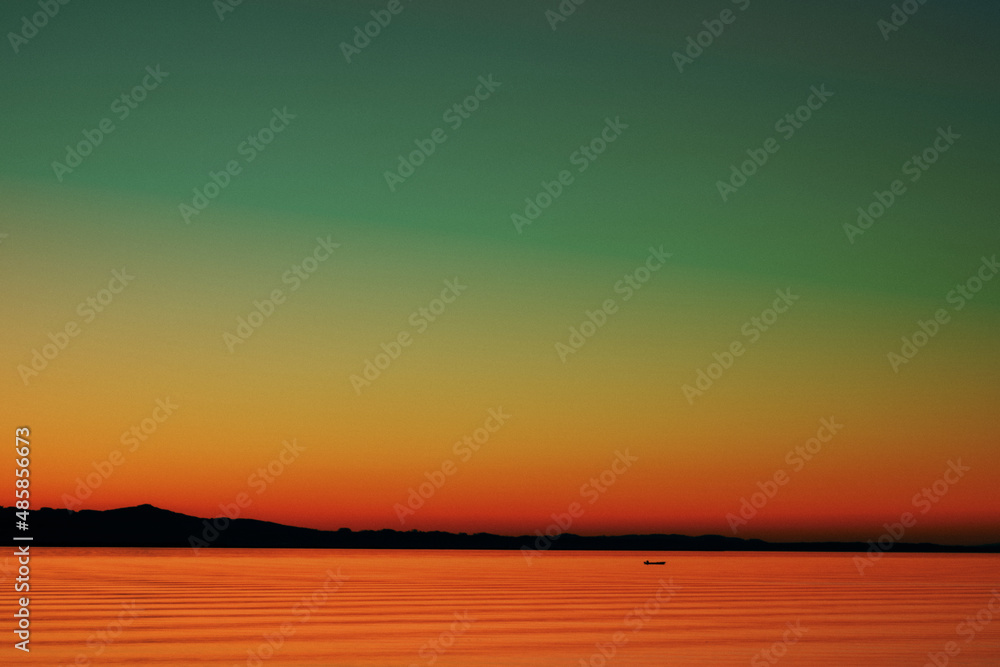 A colorful sunset over the sea with the mountains on the horizon
