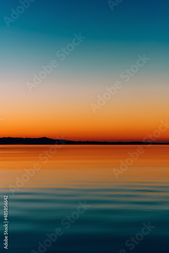 A colorful sunset over the sea with the mountains on the horizon