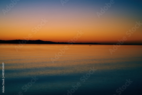 A colorful sunset over the sea with the mountains on the horizon © Erika