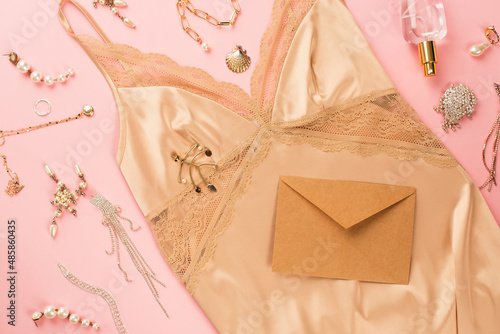 Obraz na płótnie Top view of envelope, golden accessories and camisole on pink background