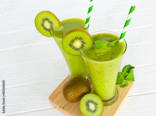Kiwi yogurt fruit juice smoothie and green kiwi juice drink healthy, delicious taste in a glass for weight loss on a white wooden background.