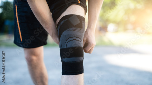 Knee support brace on male legs outdoors in summer, close up