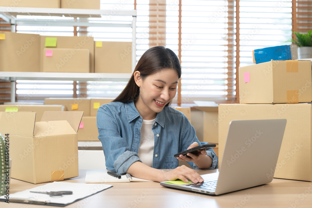 Young Asian woman owner of small online store packing customer orders in the home office. Young Asian woman owner of small online store packing customer orders in the home office.