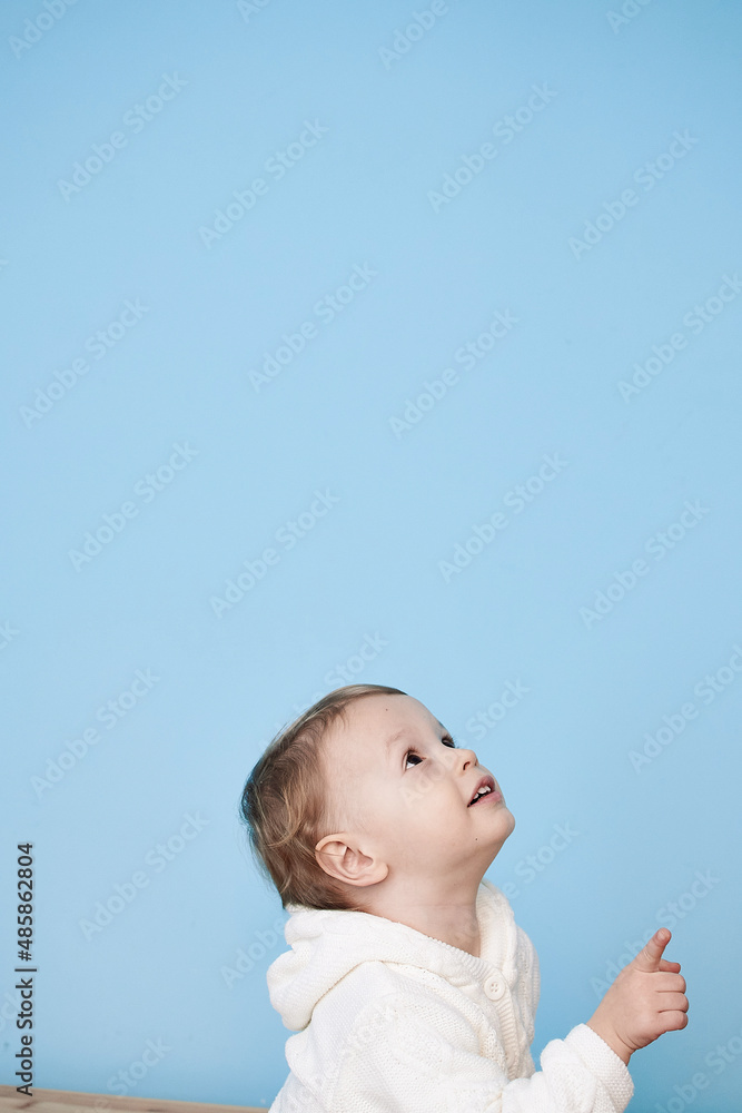 a little boy of 2 years sits in a white jacket on a blue background and thinks laughs happy sad sadness cheerful advertisement for children a little boy of 2 years sits in a white jacket on a blue background and thinks laughs happy sad sadness cheerful advertisement for children