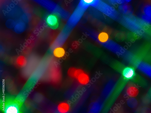 Abstract blurred bokeh background multicolor lights with cross filter. A twinkling garland, concept of Christmas and winter holidays.