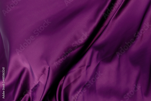Purple violet satin cloth lies crumpled in waves