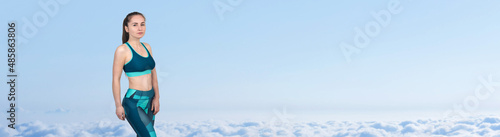 A young slim athletic girl in sportswear performs a set of exercises. Fitness and healthy lifestyle against the background of clouds sky.