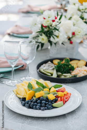 Close up image of a plate with sliced fruit and berries on a banquet table