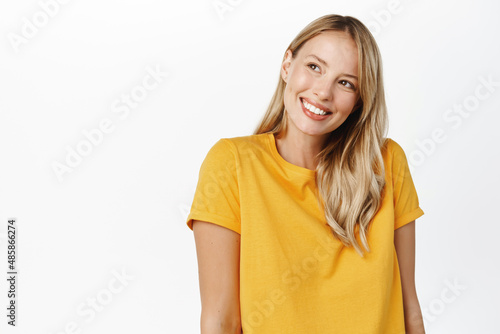 Portrait of happy modern woman, beautiful girl with white smile, bloind hair and clear natural skin without makeup, standing over white background