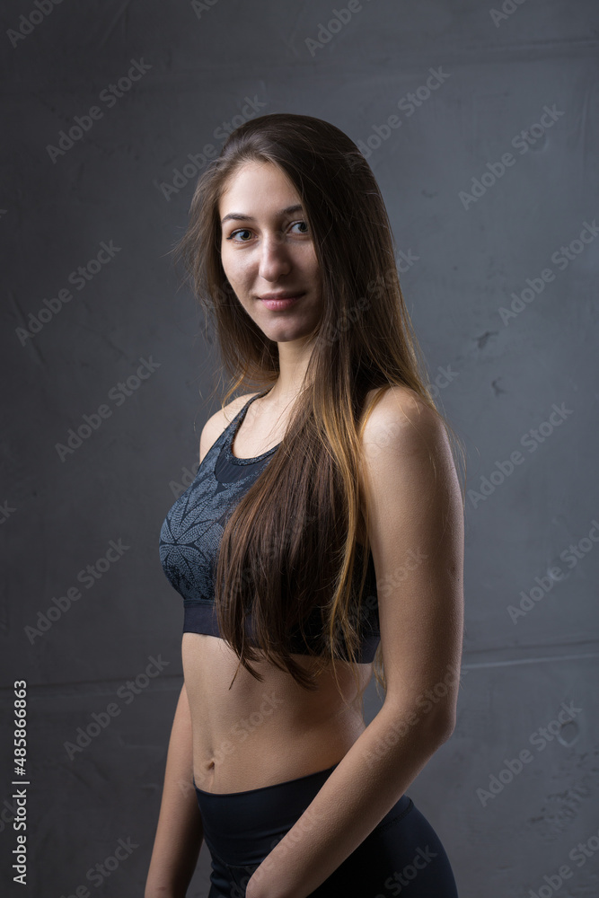 Portrait of a slender athletic young girl against a concrete wall in a fashionable apartment interior. Portrait of a slender athletic young girl against a concrete wall in a fashionable apartment interior.