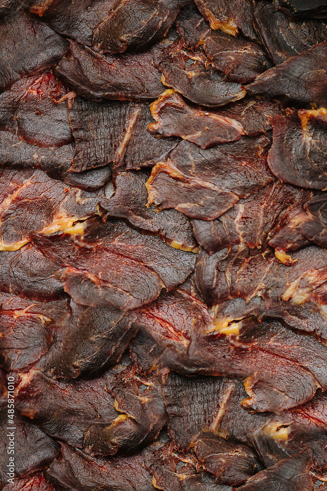 Smoked meat slices in a texture. Looking delicious. Dark shade with some yellow cooked fat.