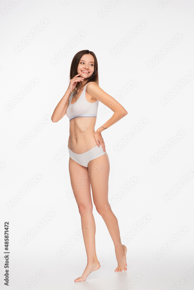 happy woman in underwear looking away while standing with hand on hip on white background happy woman in underwear looking away while standing with hand on hip on white background