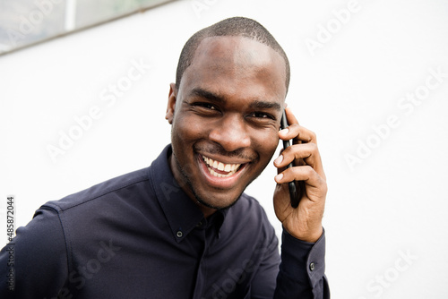 Close up happy African American man laughing with cellphone by white background