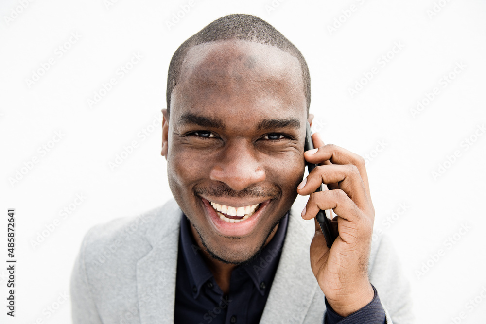 Close up smiling black business man talking with mobile phone by isolated white background Close up smiling black business man talking with mobile phone by isolated white background