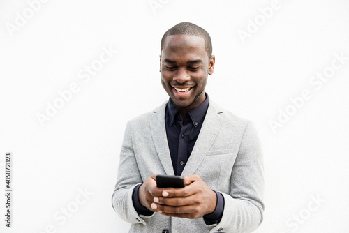 smiling black businessman using cellphone by isolated white background