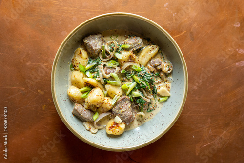 Delicious gnocchi and steak dinner with broccolini and green onions