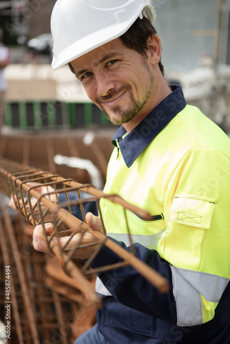 Fotografija male worker holding a metal reinforcing bar structure