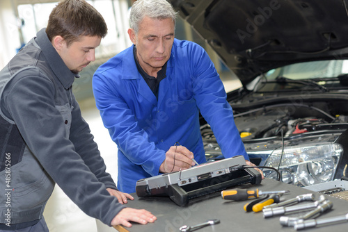 auto mechanic teacher and trainee performing tests at mechanic school