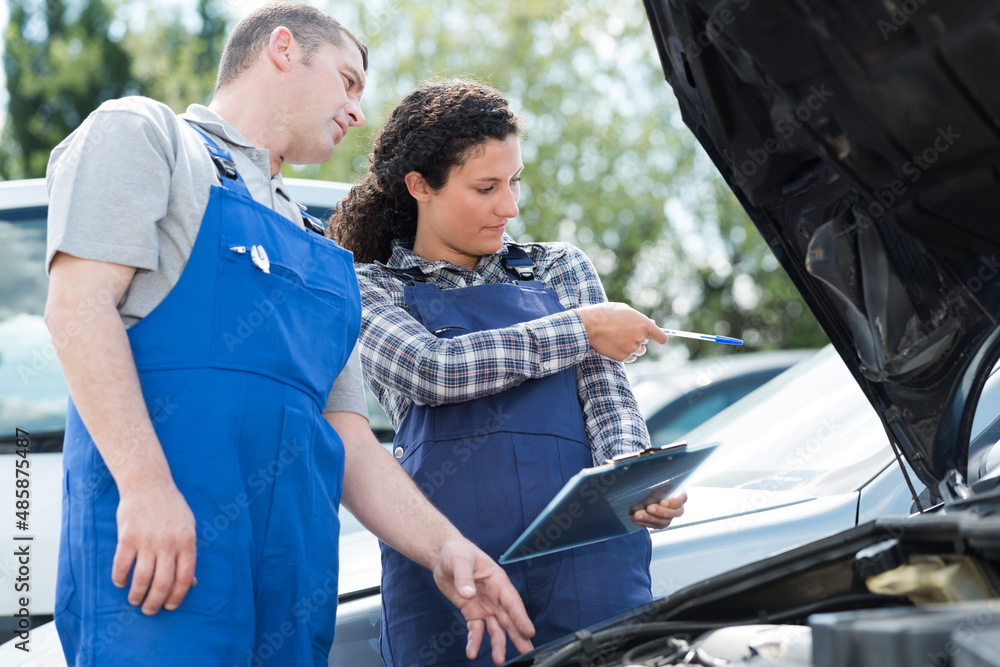 two workers looking at car documents outdoors two workers looking at car documents outdoors