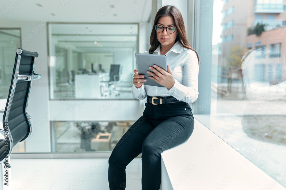 Beauty business woman using her digital tablet while working in a modern startup office. Beauty business woman using her digital tablet while working in a modern startup office.