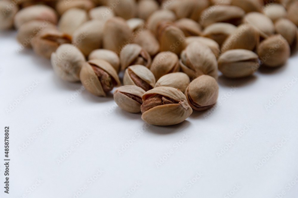 Roasted salted pistachios in a basket, plate on a white background Roasted salted pistachios in a basket, plate on a white background
