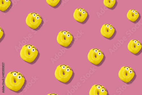 Colorful pattern of yellow glazed donuts isolated on pink background with shadows. Doughnuts. Top view. Flat lay