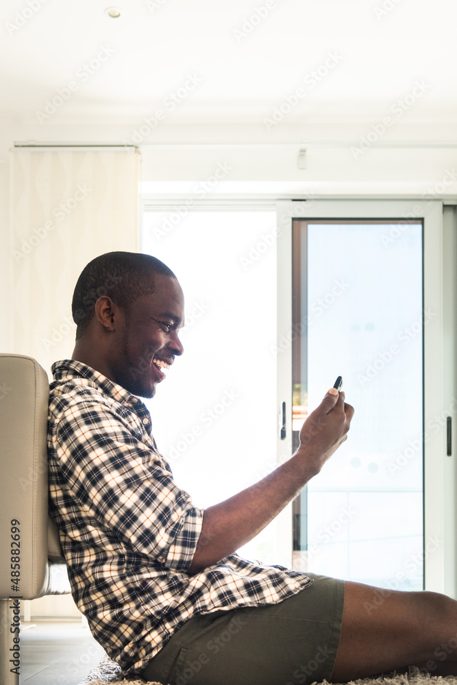 portrait happy african american man sitting on floor with cellphone