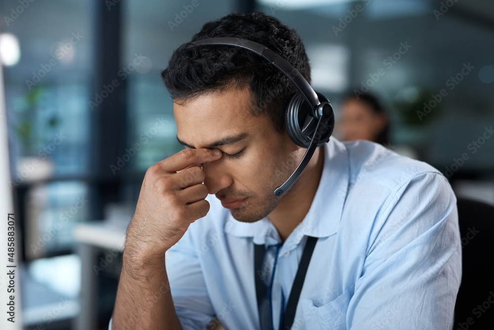 Help yourself before you help others. Shot of a young man using a headset and looking stressed in a modern office. - obrazy, fototapety, plakaty 