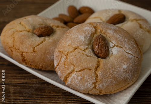 Gluten free italian cookies and almond on saucer. Almond cookies. Sicilian traditional almond biscuits. Biscotti di mandorla siciliani.