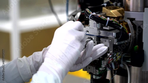 Gloved hands removing a sample from an electron microscope photo