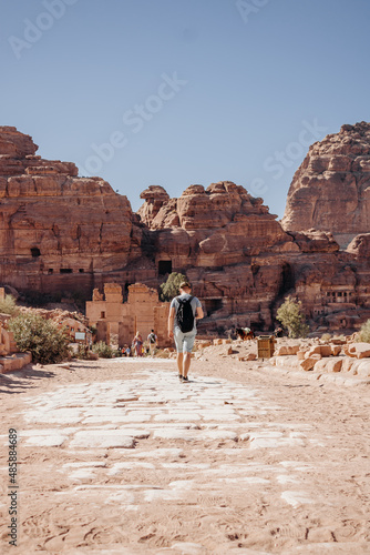 Tourist man with a backpack exploring the sights of the ancient, fabulous city of Petra in Jordan. Colorful photos. Vacation, vacation and travel concept