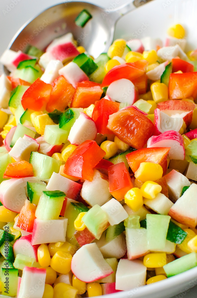 salad of cucumbers, corn, bell peppers and crab sticks. Close-up, vertical photo. salad of cucumbers, corn, bell peppers and crab sticks. Close-up, vertical photo.