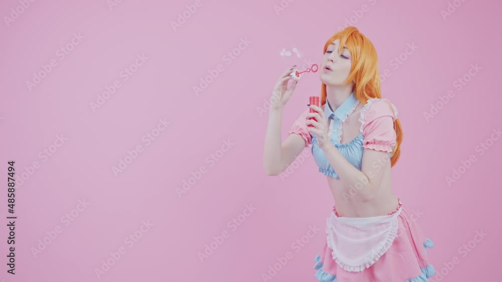 Caucasian Model Flirts With Camera By Slowly Blowing Shiny Bubbles Medium Long Studio Shot Pink Background. High quality 4k footage Caucasian Model Flirts With Camera By Slowly Blowing Shiny Bubbles Medium Long Studio Shot Pink Background. High quality 4k footage