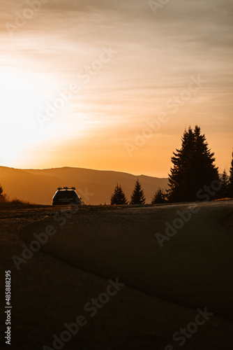 Silhouette of trees and car with a beautiful sunset in the background.