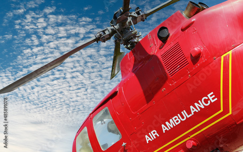 Red helicopter of air ambulance isolated against blue sky and clouds  background. Detail of the helicopter blades. First aid and emergency concept