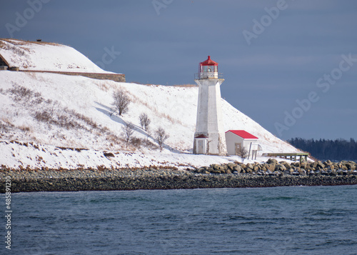  Lighthouse covered in snow on sunny winter day.