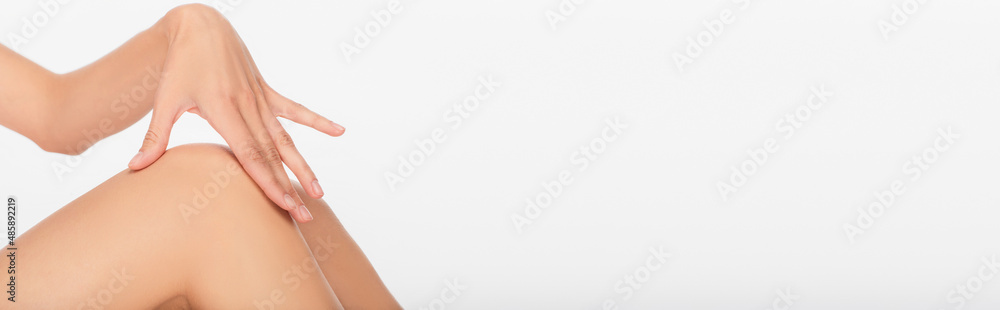 cropped view of woman with smooth skin touching knee isolated on white, banner